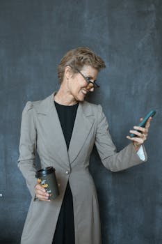 Confident senior businesswoman smiling at her smartphone in a modern office setting.