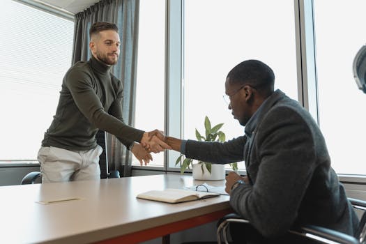 Two businessmen shaking hands in a modern office after a successful meeting or interview.