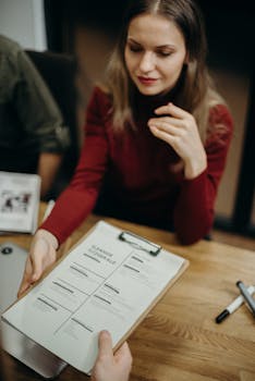 Woman sitting at a desk holding a clipboard and reviewing a resume during a job interview.