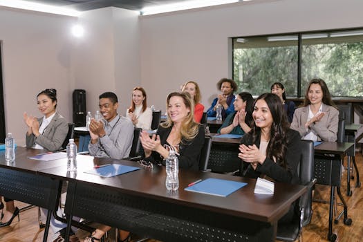 A diverse group of adults applauding in a business seminar setting.