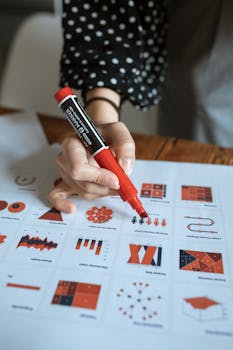 A person highlights data on a sheet with charts using a red marker.