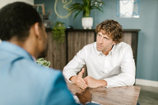 Men in office attire having a focused conversation at a wooden table.