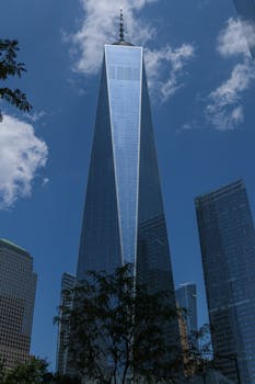 One World Trade Center towering in New York City, capturing its modern architecture against a clear blue sky.