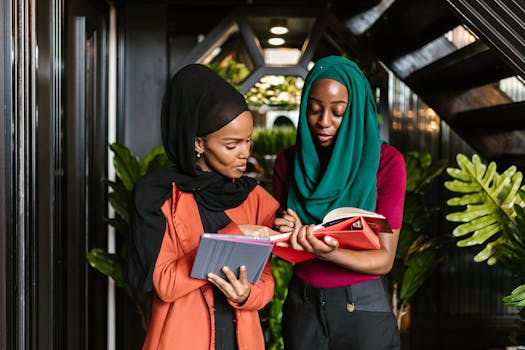 Two women in business attire reviewing documents indoors, conveying a professional teamwork atmosphere.